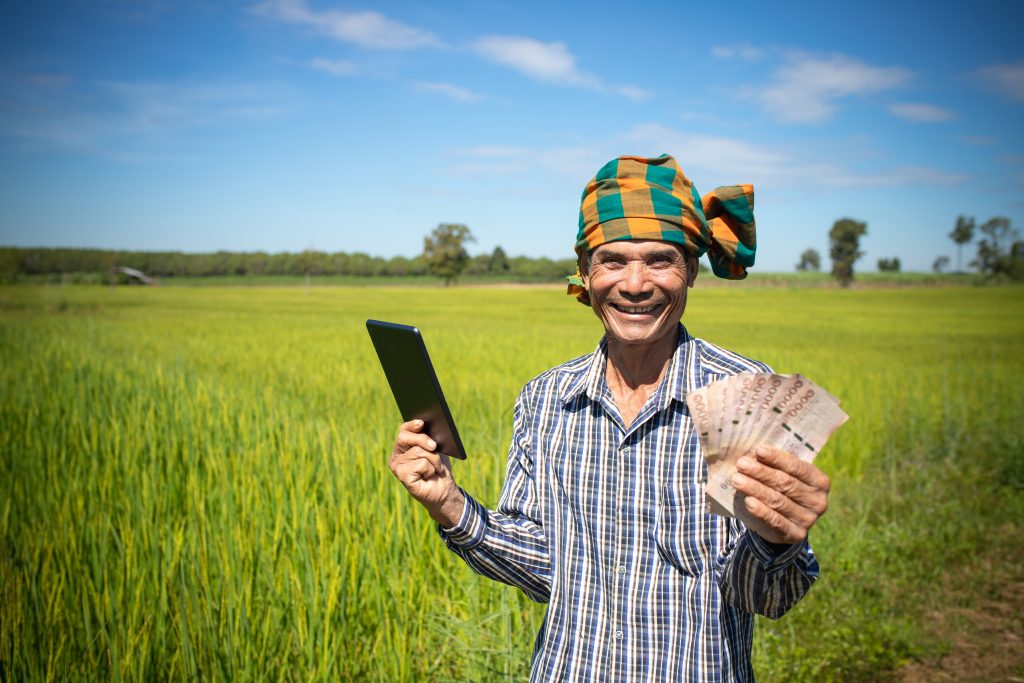 happy asian man farmer with smiling face hand holding smart phone standing rice farm cash subsidy concept