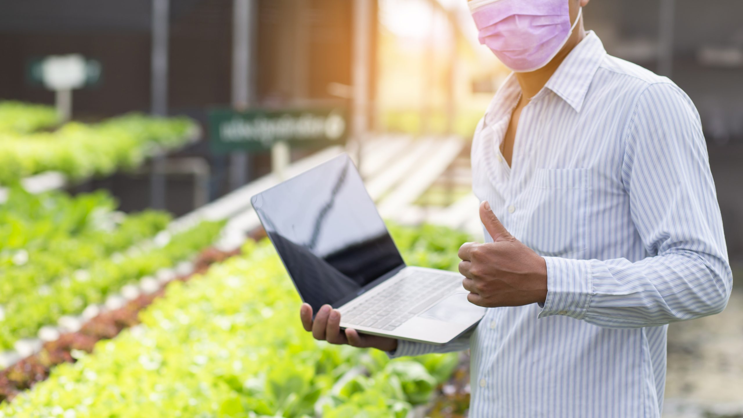 organic farmer stands a great thumbs up.